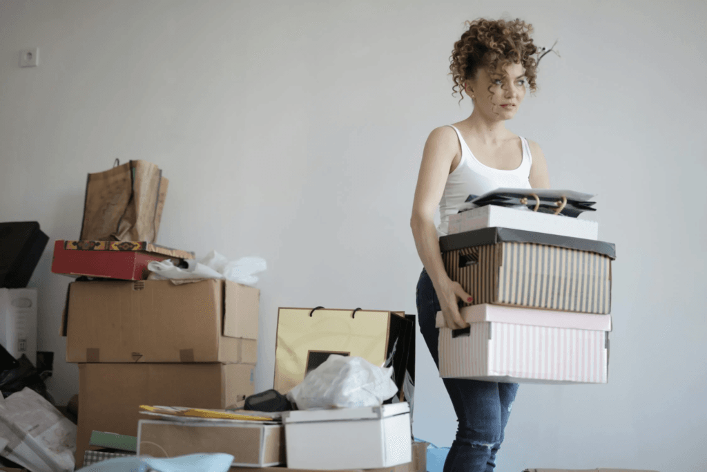 A woman struggles to carry boxes of clutter.