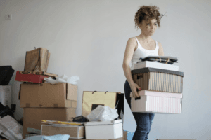 A woman struggles to carry boxes of clutter