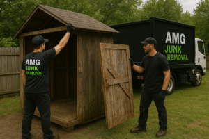 AMG Junk Removal team clearing junk from a residential garage with their branded truck ready for pickup