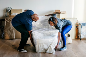A Couple lifting a couch as part of their furniture disposal before moving