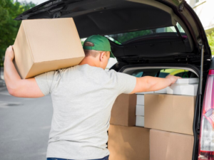 Man lifting heavy boxes alone during a dump run, risking physical strain and back injury