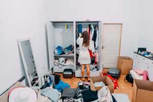 Woman sorting through belongings in a cluttered room while embracing a minimalist lifestyle