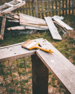 A paintbrush resting on wooden planks during a yard project